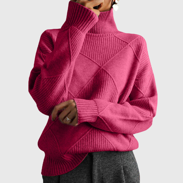 Model wearing pink oversized turtleneck sweater with arms crossed, front view