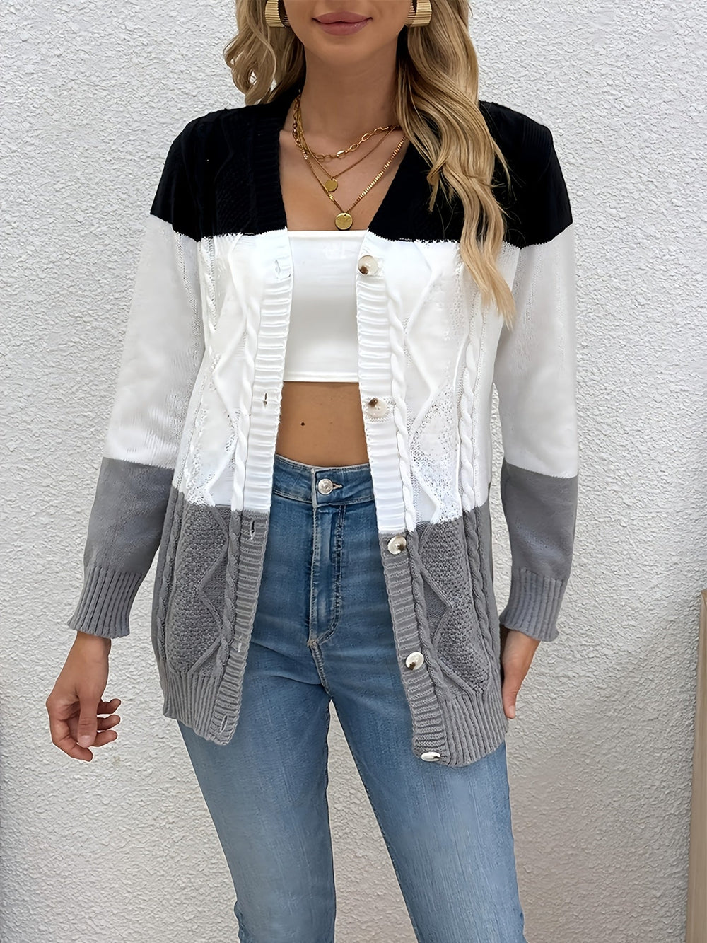 Colette colorblock cable knit cardigan, standing front view against textured wall