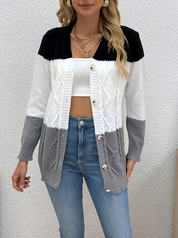 Colette colorblock cable knit cardigan, standing front view against textured wall