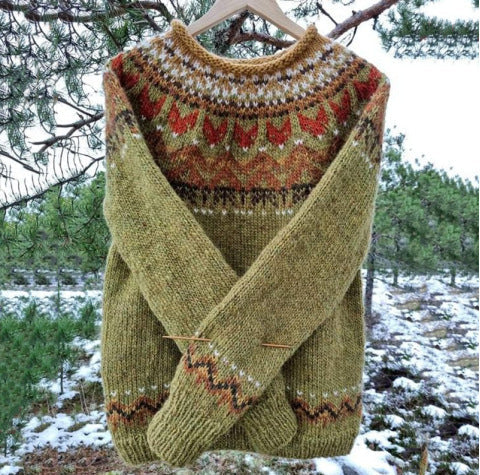 Freya Icelandic knit sweater in green colorway hanging outdoors in a snowy pine setting