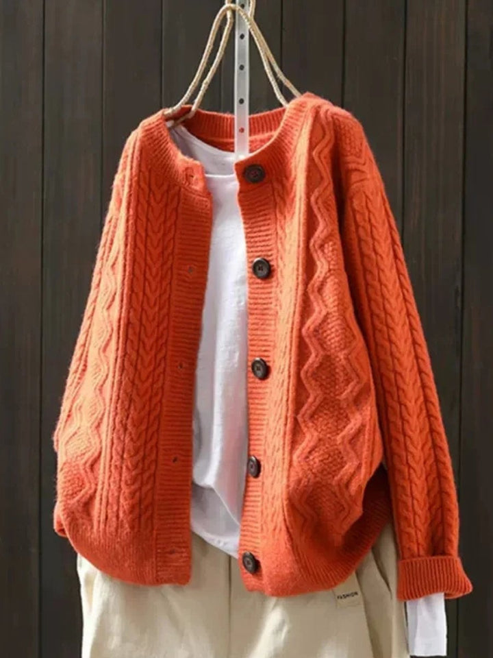 Josephine oversized cable knit cardigan in orange, front view on hanger