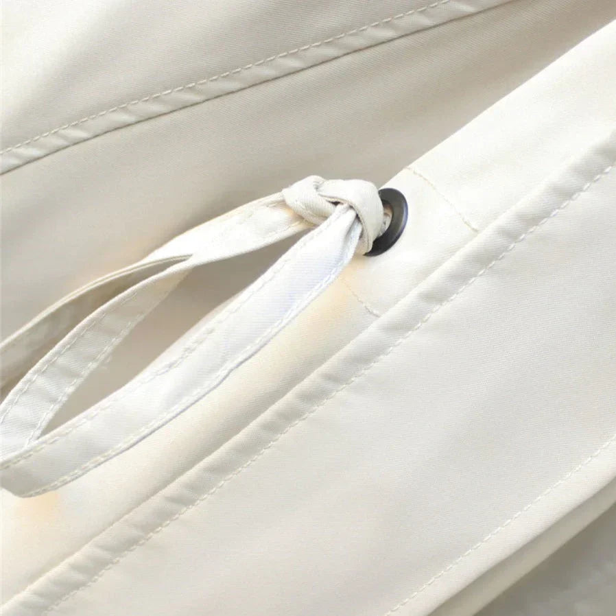 Close-up of drawstring cord and button loop on cream side of Margaux trench coat