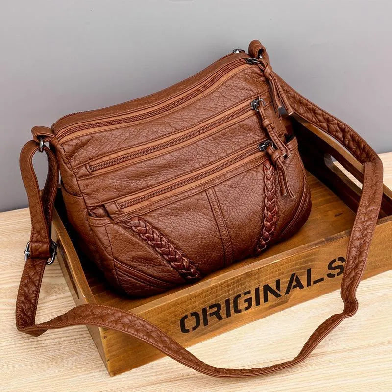 Rosalind braided crossbody shoulder bag in brown, front view on wooden crate