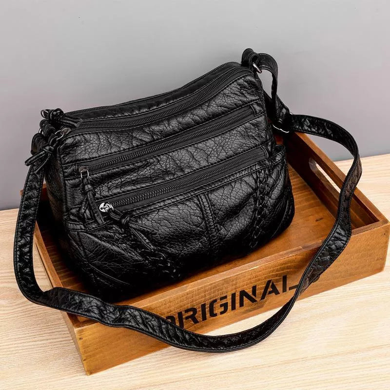 Rosalind braided crossbody shoulder bag in black, front view on wooden crate