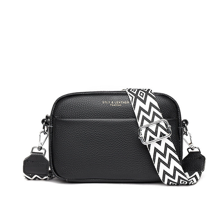 Rosalind crossbody bag in cream held in hand with patterned strap detail
