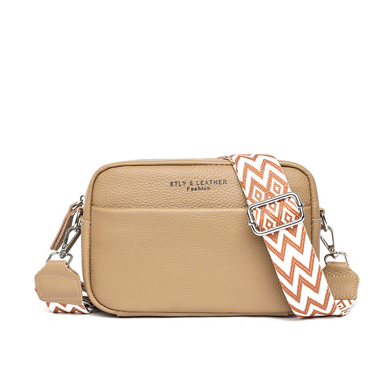 Rosalind crossbody bag in cream held in hand with patterned strap detail