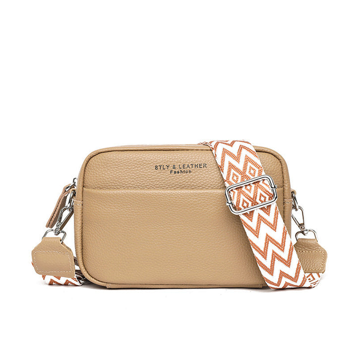 Rosalind crossbody bag in cream held in hand with patterned strap detail