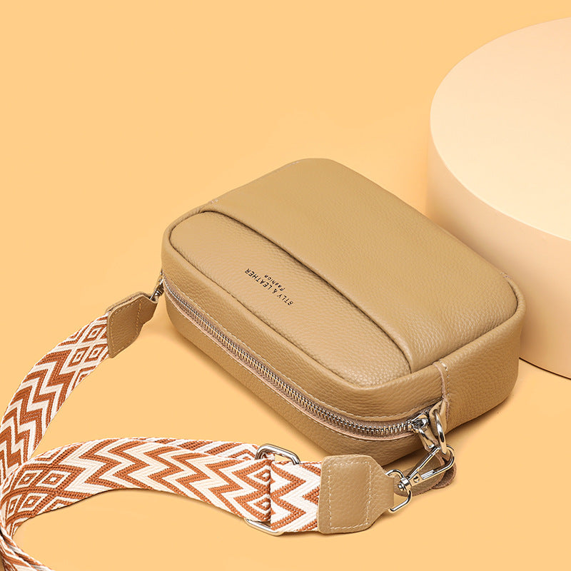 Rosalind crossbody bag in cream held in hand with patterned strap detail