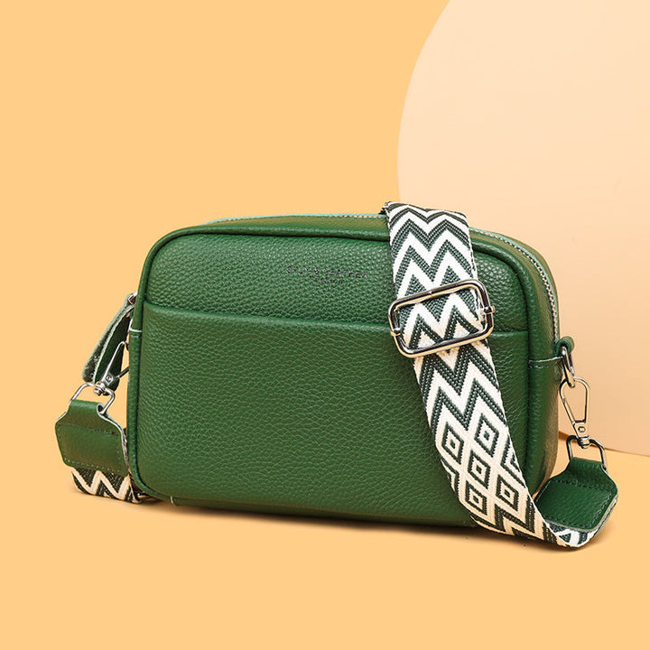 Rosalind crossbody bag in cream held in hand with patterned strap detail