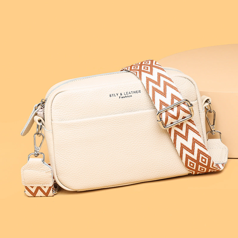 Rosalind crossbody bag in cream held in hand with patterned strap detail