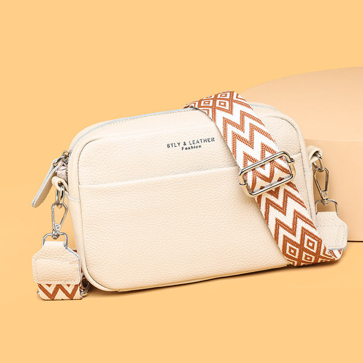 Rosalind crossbody bag in cream held in hand with patterned strap detail