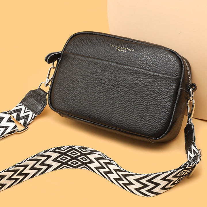Rosalind crossbody bag in cream held in hand with patterned strap detail