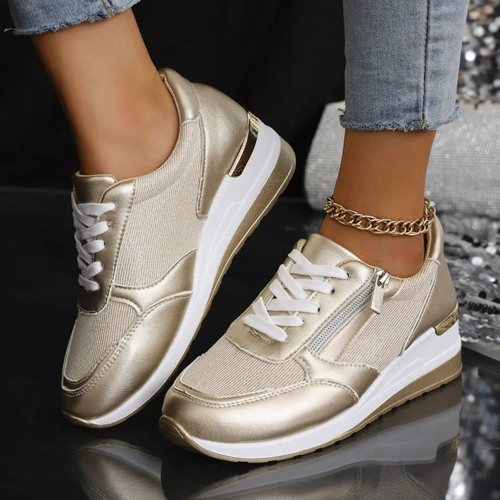 Faustine gold walking sneakers worn on feet, close-up