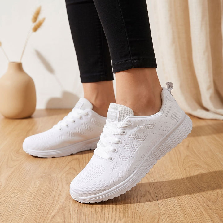 White lace-up mesh sneakers close-up showing cushioned sole and textured upper