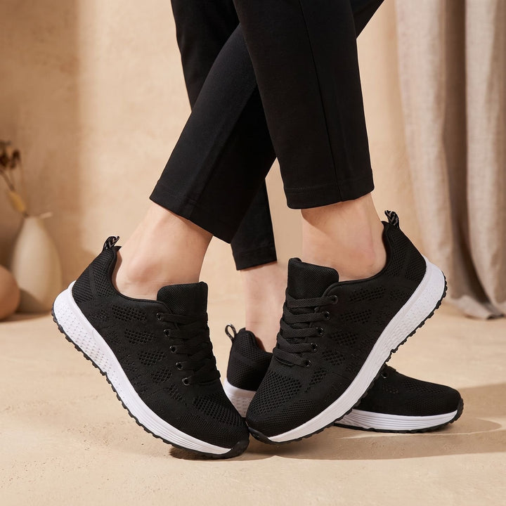 White lace-up mesh sneakers close-up showing cushioned sole and textured upper