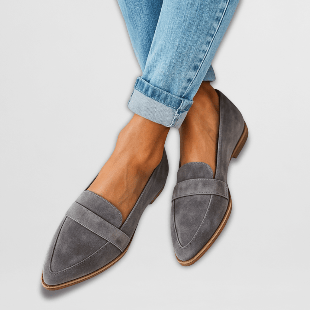 Gray suede pointed toe loafers worn with cuffed jeans, crossed ankles view