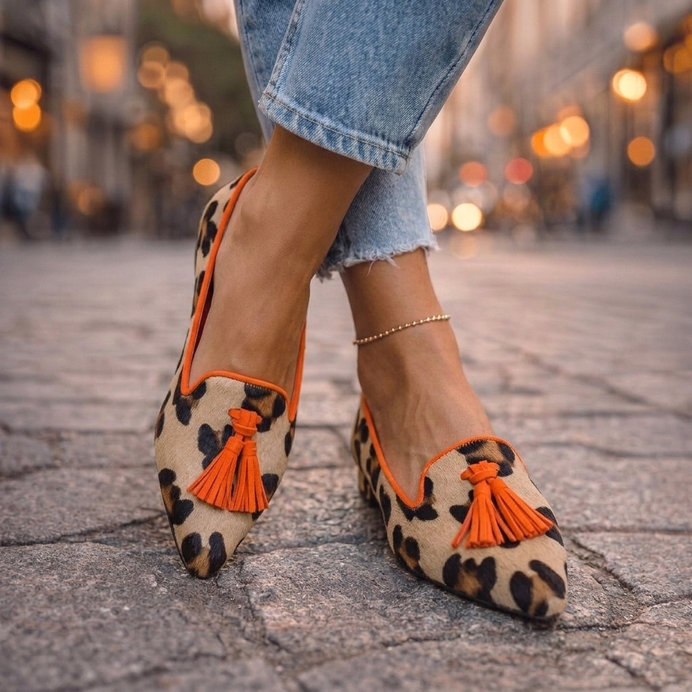 Marcelline orange leopard print tassel loafers, side view on cobblestone street