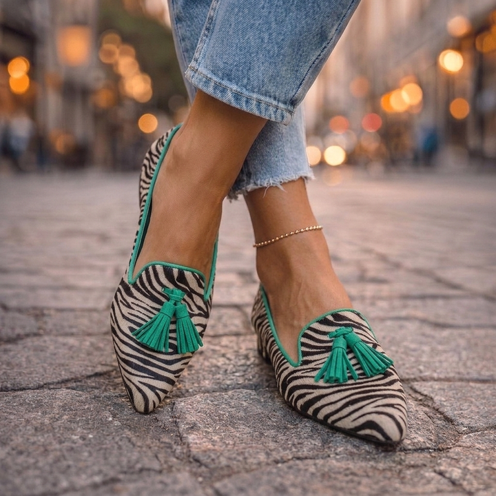 Marcelline green zebra print tassel loafers, side view on cobblestone street