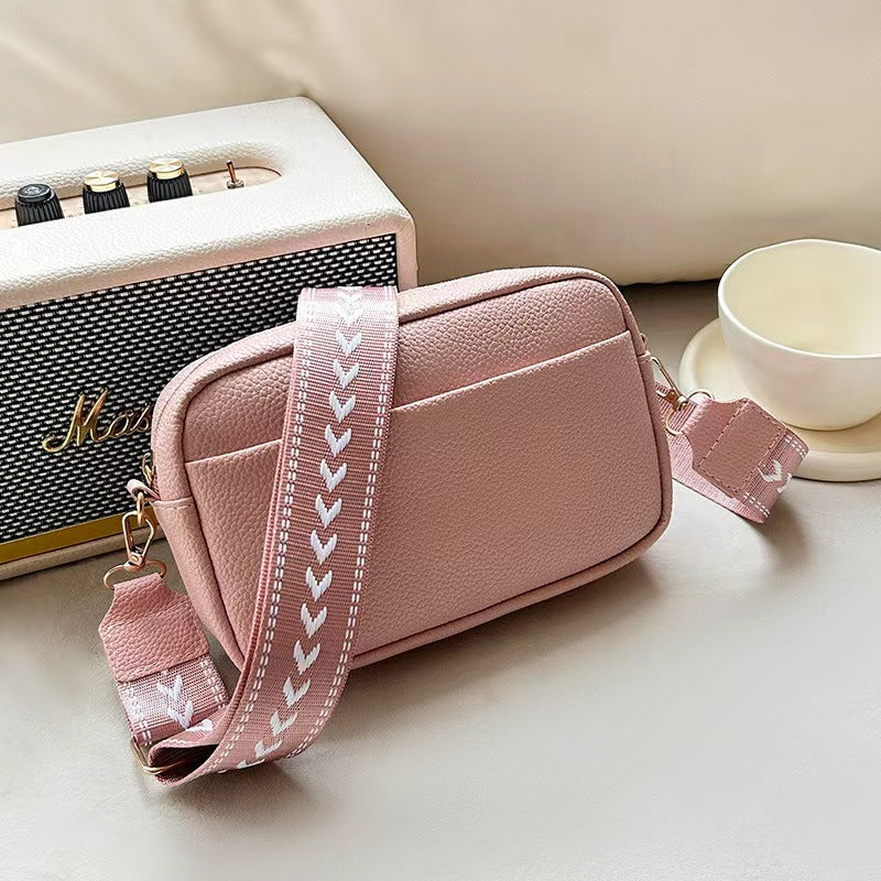 Vivienne pink leather crossbody bag with striped strap, side view